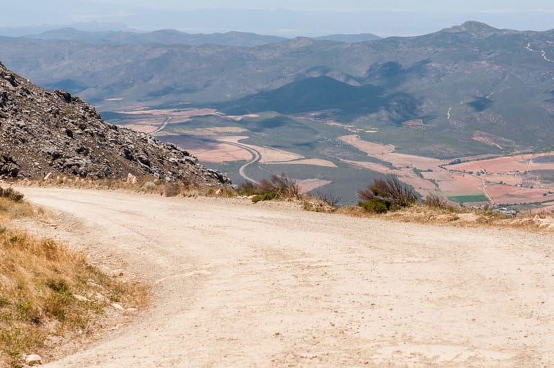 Blick von einer Schotterstraße hoch am Berg über Täler und Felder